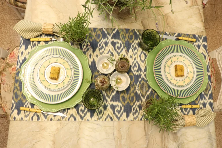 Blue and green table setting with layered dinnerware, rosemary plants and textured green glassware for elegant everyday dining