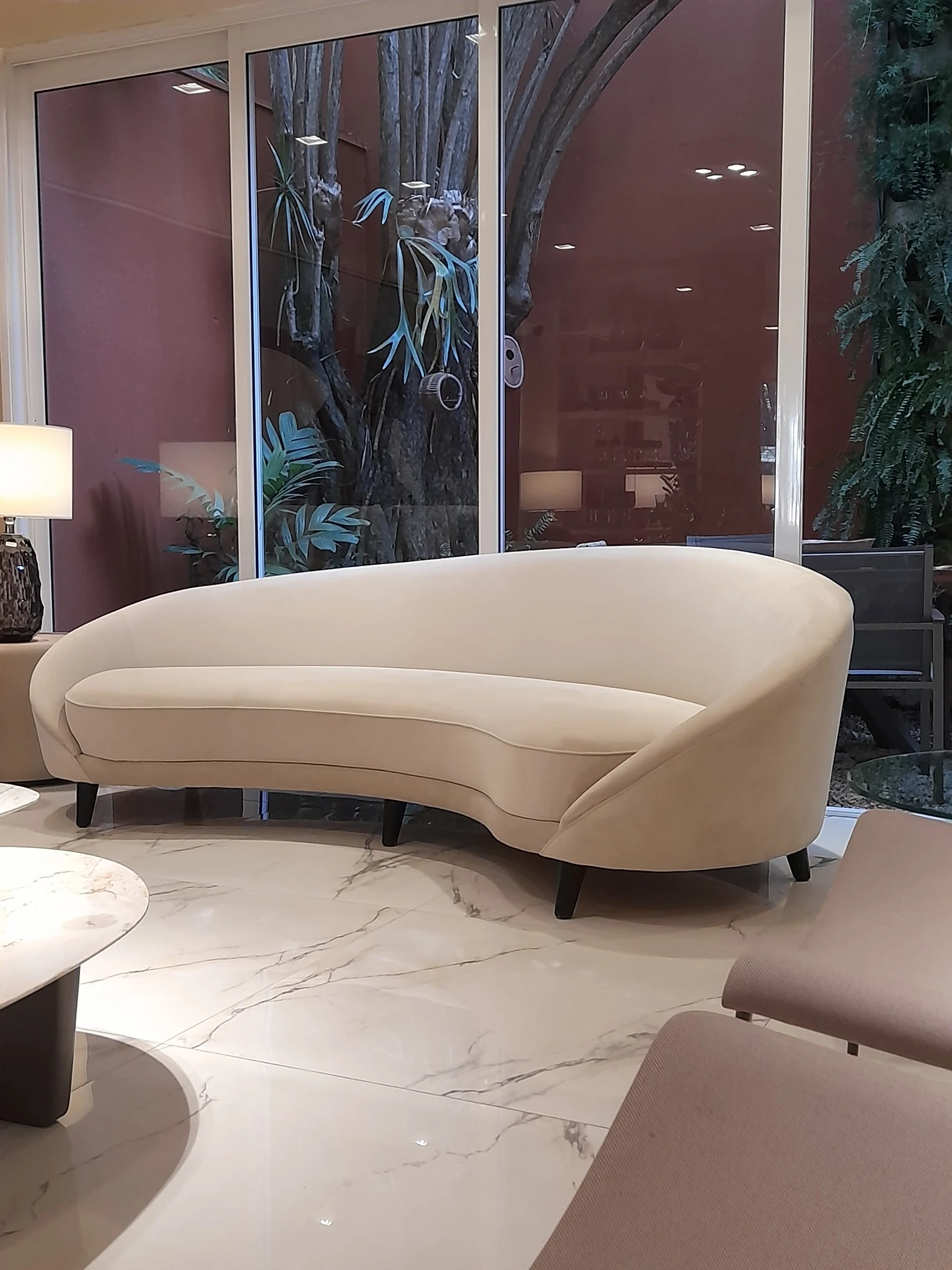 Curved cream sofa upholstered in textured fabric in an elegant contemporary living room