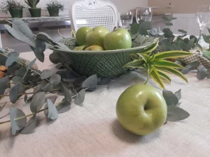 Green apple centerpiece with eucalyptus creating a natural focal point for an elegant dining table