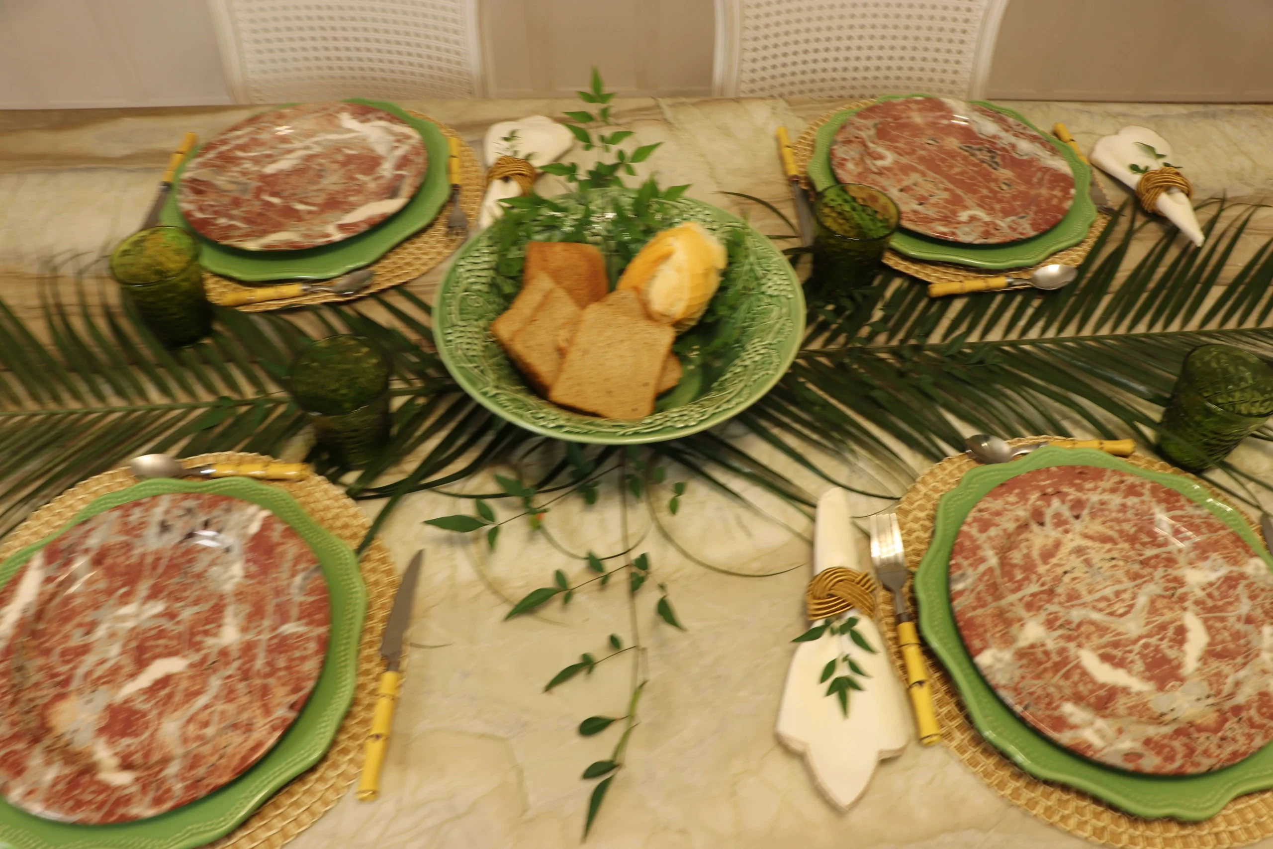 Decorative-dinner-plates-layered-over-green-chargers-and-woven-placemats-for-a-balanced-table-setting