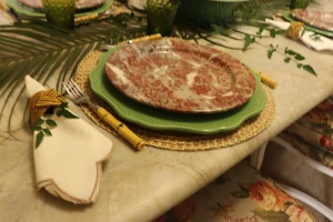 Layered place setting with a woven placemat, green charger, and decorative marble dinner plate