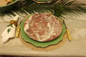 Marble-pattern-decorative-dinner-plate-layered-with-a-green-charger-and-woven-placemat