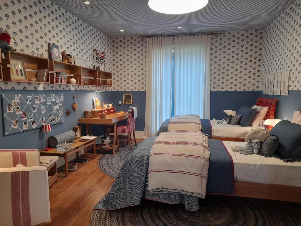Spacious-shared-kids-bedroom-with-twin-beds-study-desk-layered-storage-and-coordinated-blue-and-red-decor.